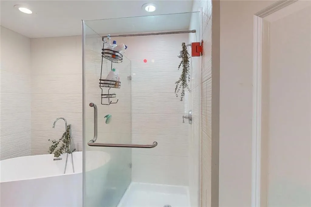 Bathroom with a stall shower, a freestanding bath, and recessed lighting