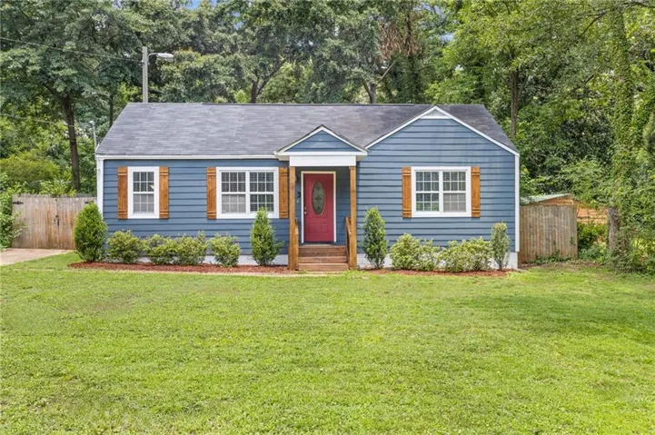 Blue siding exterior with a dark red entry door, white trim windows, and wooden shutters