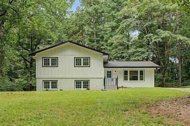 Split-level residence featuring a white painted brick lower level and vertical siding upper level