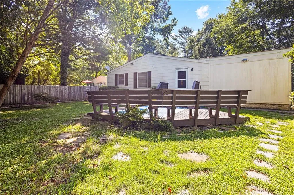 Rear view of house with a fenced backyard, a deck, and a pool