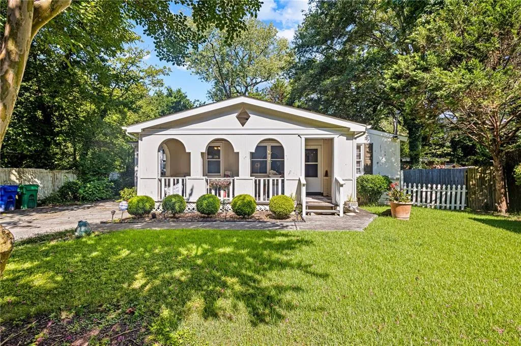 View of front of house with covered porch, stucco siding, and view of scattered trees