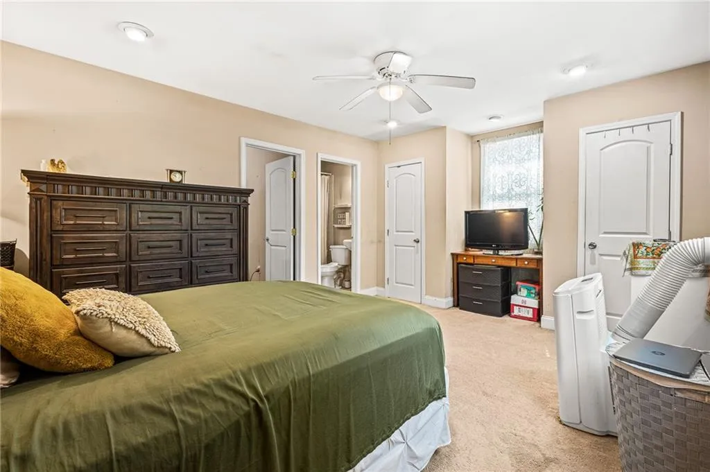 Bedroom with light colored carpet and connected bathroom