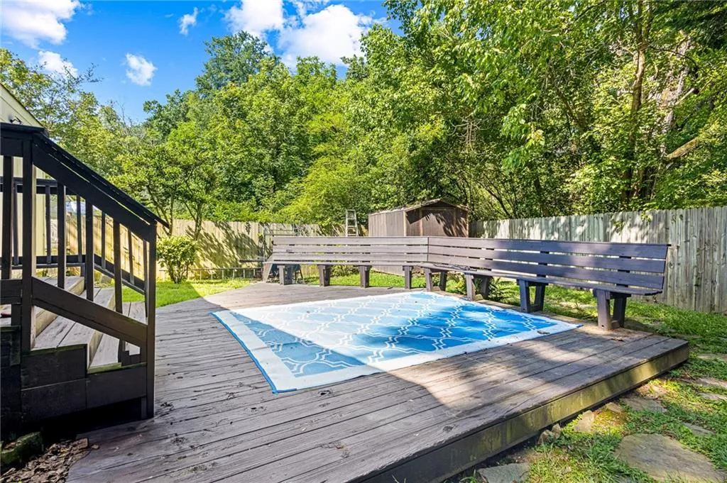 View of swimming pool with a wooden deck, a shed, and a fenced backyard
