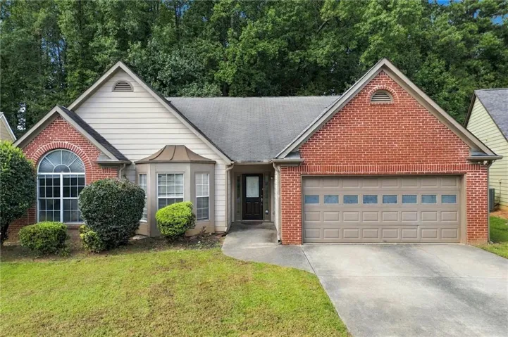 Red brick facade with siding accents, arched transom window, bay window, and attached garage