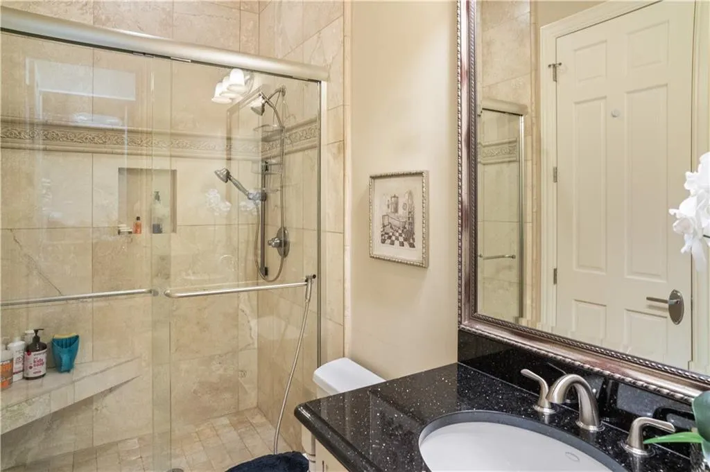 Bathroom featuring a shower with door, vanity, and toilet Bathroom featuring a shower with door, vanity, and toilet