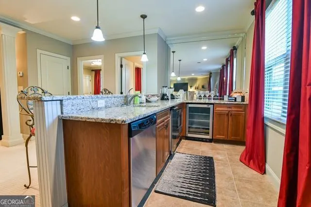 Kitchenette featuring granite countertops, wood cabinetry, stainless steel dishwasher, and built-in beverage cooler