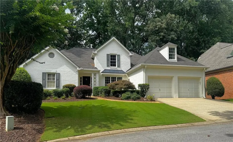 Traditional-style residence with white painted brick exterior and dark shingle roof