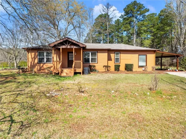 Ranch-style home with an attached carport, a front yard, covered porch, and driveway