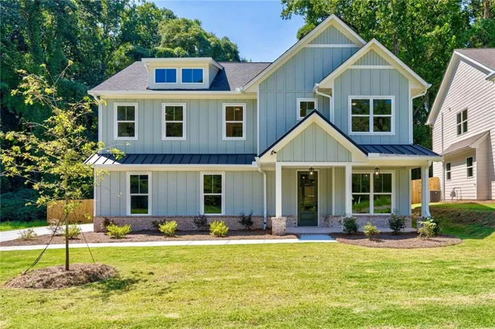 Modern farmhouse exterior featuring board and batten siding, a covered entry porch with columns, a dormer window, and a metal accent roof