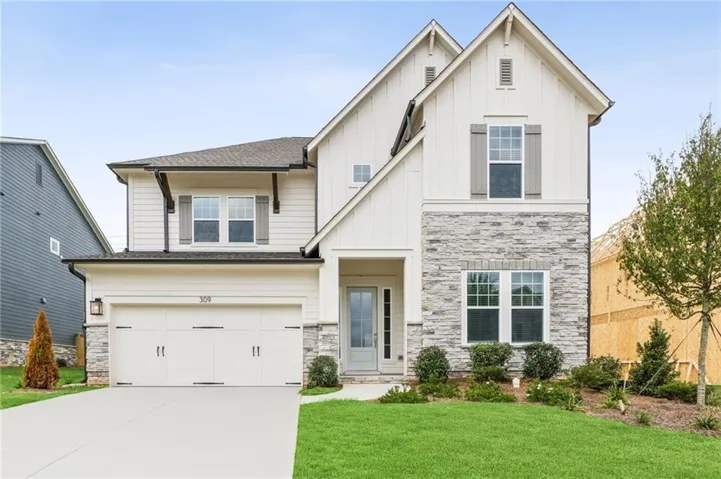 Modern farmhouse exterior featuring board and batten siding, stone facade, a two-car garage, and a concrete driveway