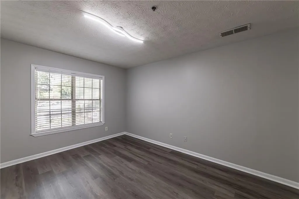 Unfurnished room with dark wood finished floors and a textured ceiling