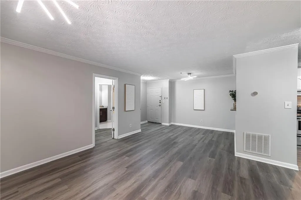 Spare room featuring a textured ceiling, ornamental molding, and dark wood-type flooring