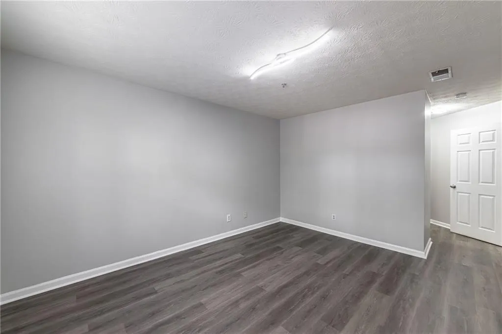 Empty room with dark wood-style flooring and a textured ceiling