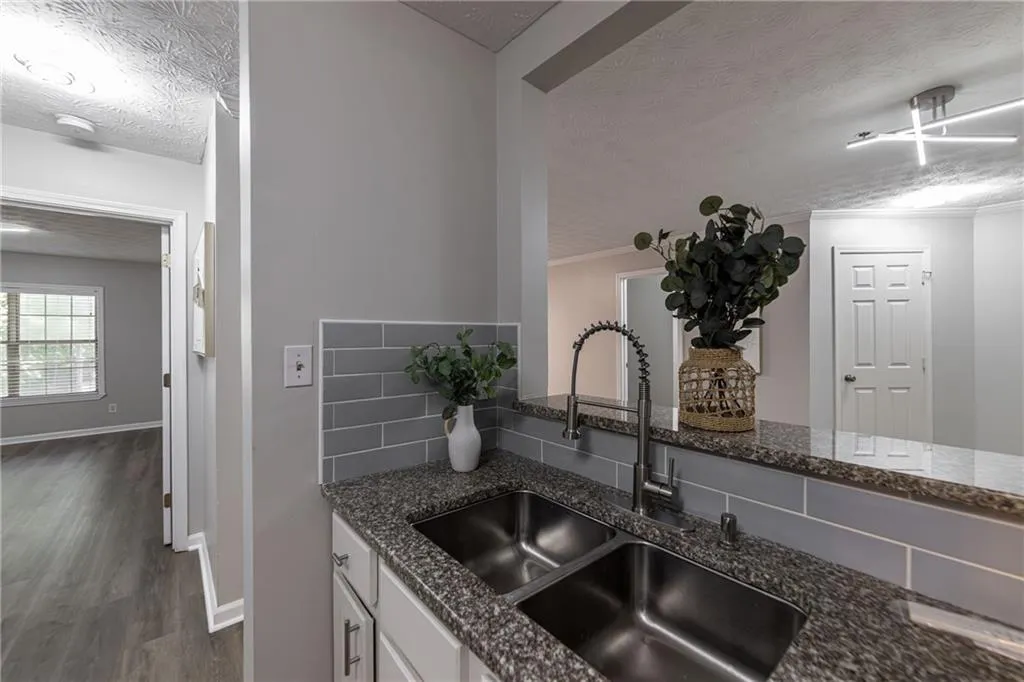 Kitchen featuring a textured ceiling, dark stone counters, dark wood-style floors, tasteful backsplash, and white cabinetry