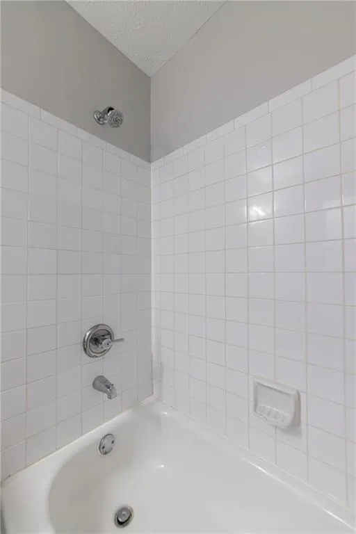 Bathroom featuring shower / tub combination and a textured ceiling