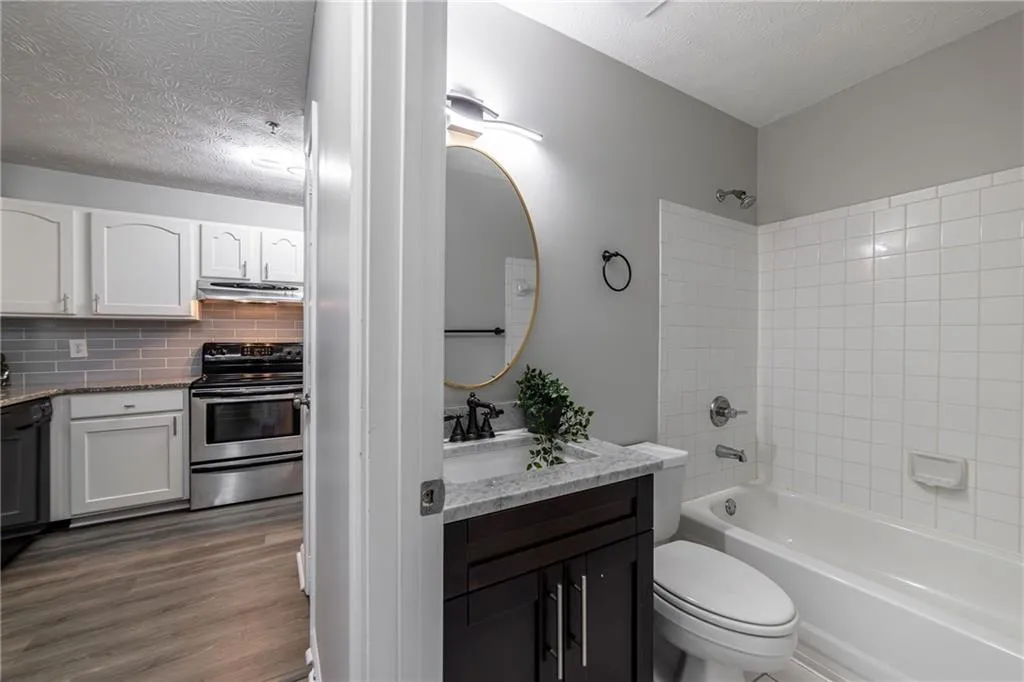 Bathroom with shower / washtub combination, vanity, a textured ceiling, backsplash, and dark wood finished floors