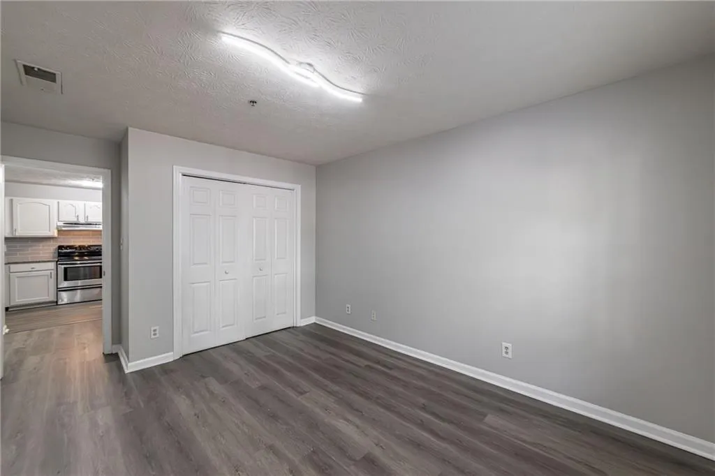 Unfurnished bedroom with dark wood finished floors, a textured ceiling, and a closet