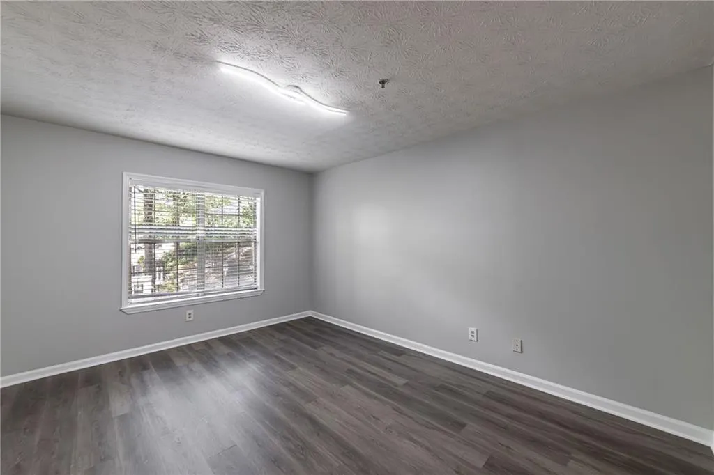 Unfurnished room featuring a textured ceiling and dark wood-style flooring