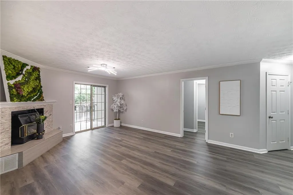 Unfurnished living room featuring ornamental molding, dark wood-style floors, a textured ceiling, and a wood stove