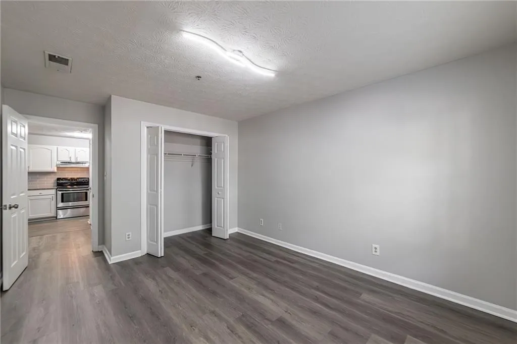 Unfurnished bedroom featuring a textured ceiling, dark wood-style flooring, and a closet