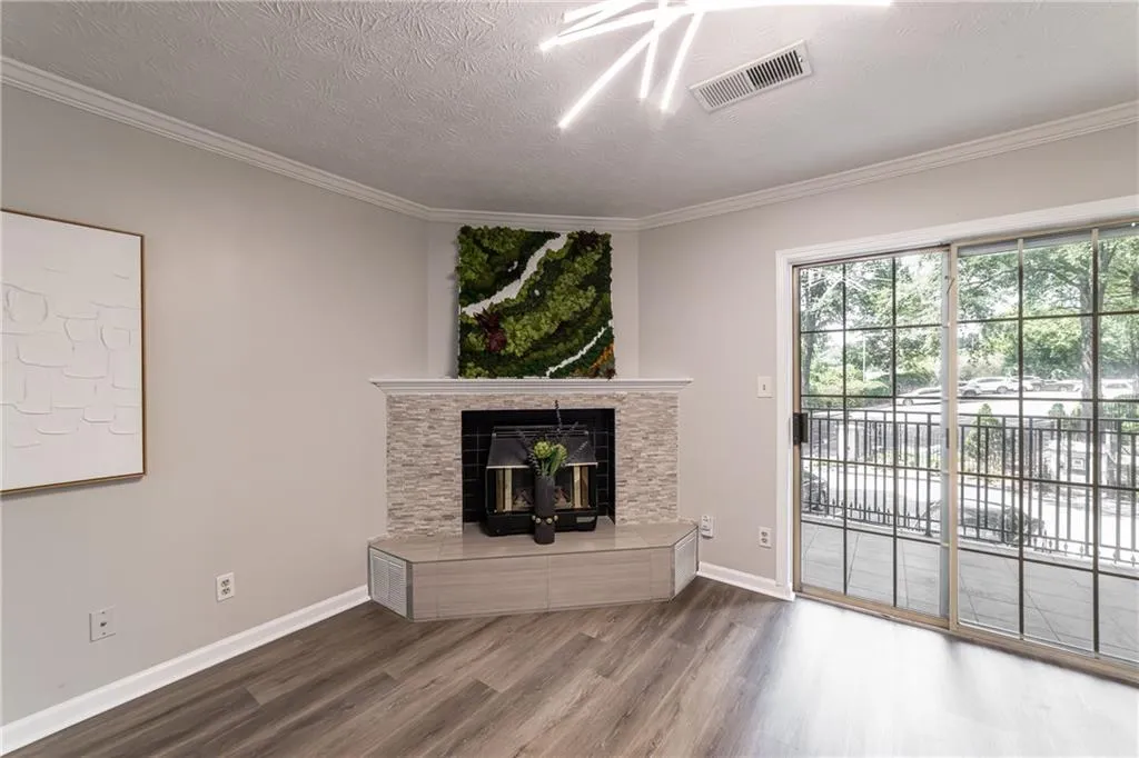 Unfurnished living room with wood finished floors, crown molding, a fireplace, and a textured ceiling