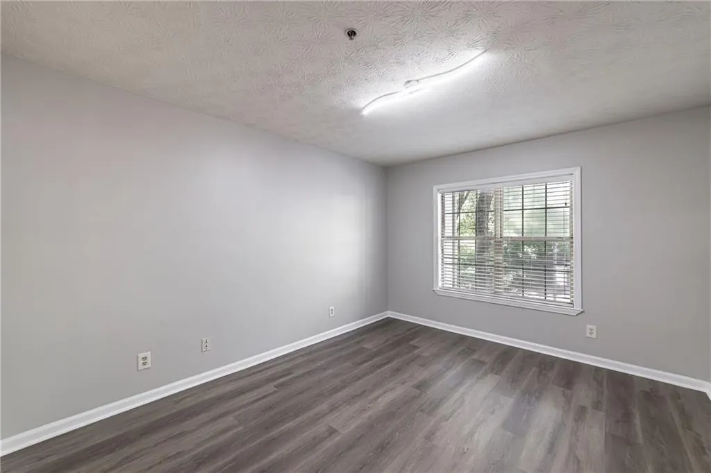 Empty room with dark wood-type flooring and a textured ceiling