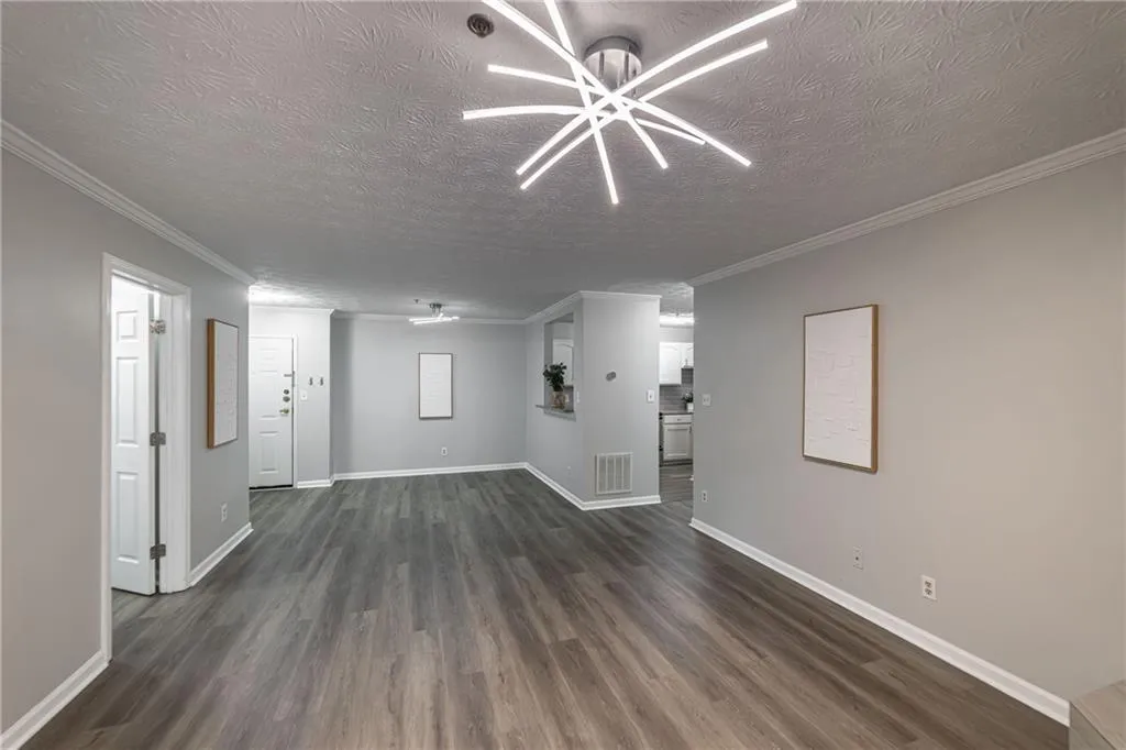 Unfurnished living room with a textured ceiling, dark wood finished floors, and ornamental molding
