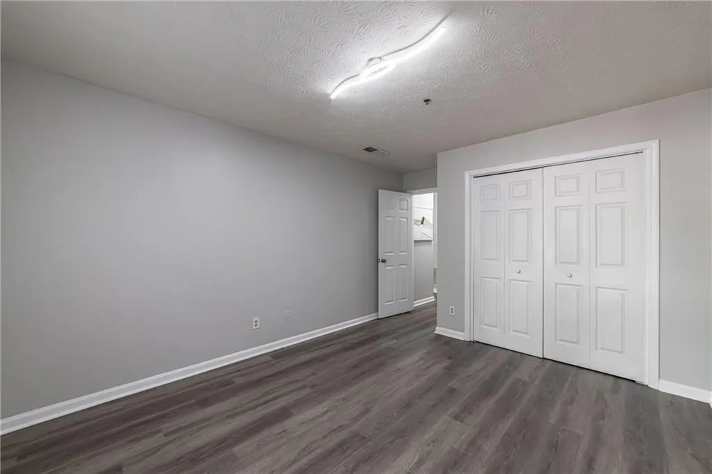 Unfurnished bedroom with a textured ceiling, dark wood finished floors, and a closet