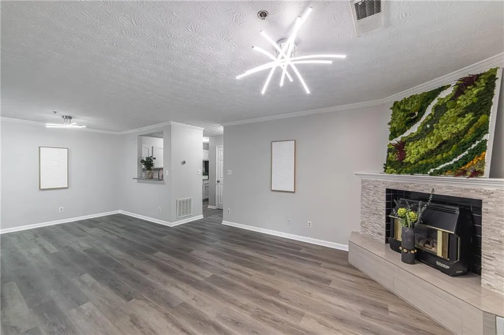 Unfurnished living room featuring wood finished floors, a textured ceiling, and ornamental molding