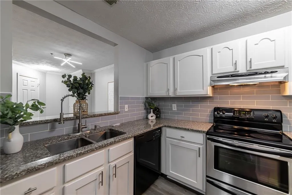 Kitchen with stainless steel range with electric stovetop, backsplash, dishwasher, under cabinet range hood, and crown molding