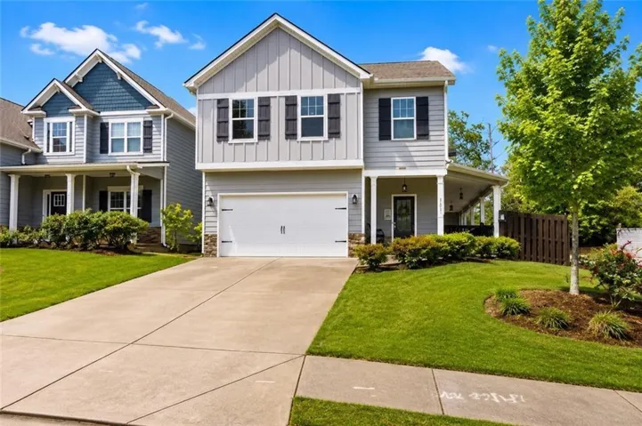 Two-story residence featuring light gray siding, black shutters, an integrated garage, a concrete driveway, and a covered side patio