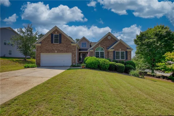 Brick-clad exterior with multiple gables, arched window, and a two-car garage