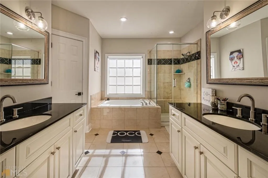 Full bathroom featuring a shower stall, light tile patterned flooring, two vanities, and a bath