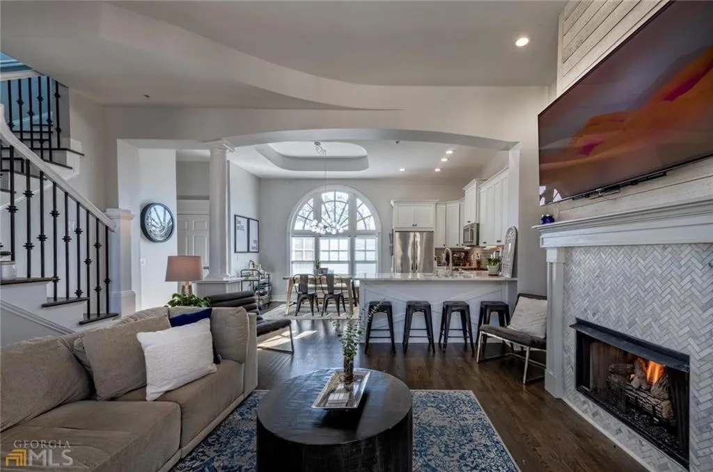 Living area with a tile fireplace, dark wood-type flooring, stairway, recessed lighting, and a tray ceiling