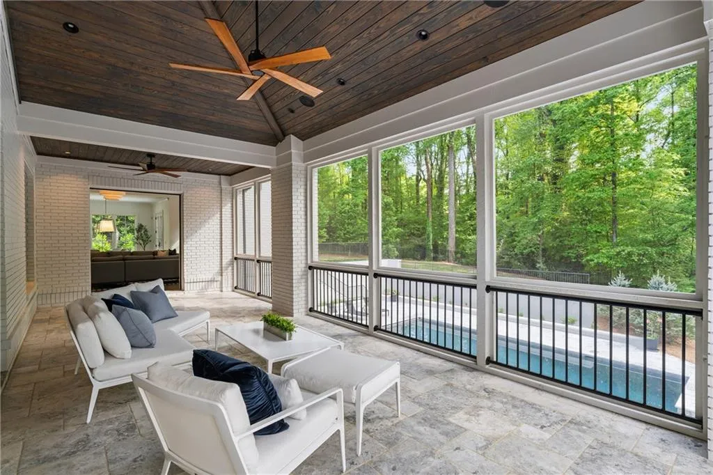 Screened-in porch off main living area and den with limestone flooring and tongue and groove ceiling