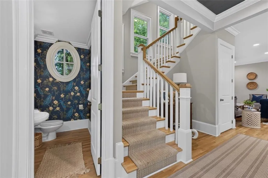 Hardwood flooring throughout the entry, staircase with wood-finish handrail, and white balusters