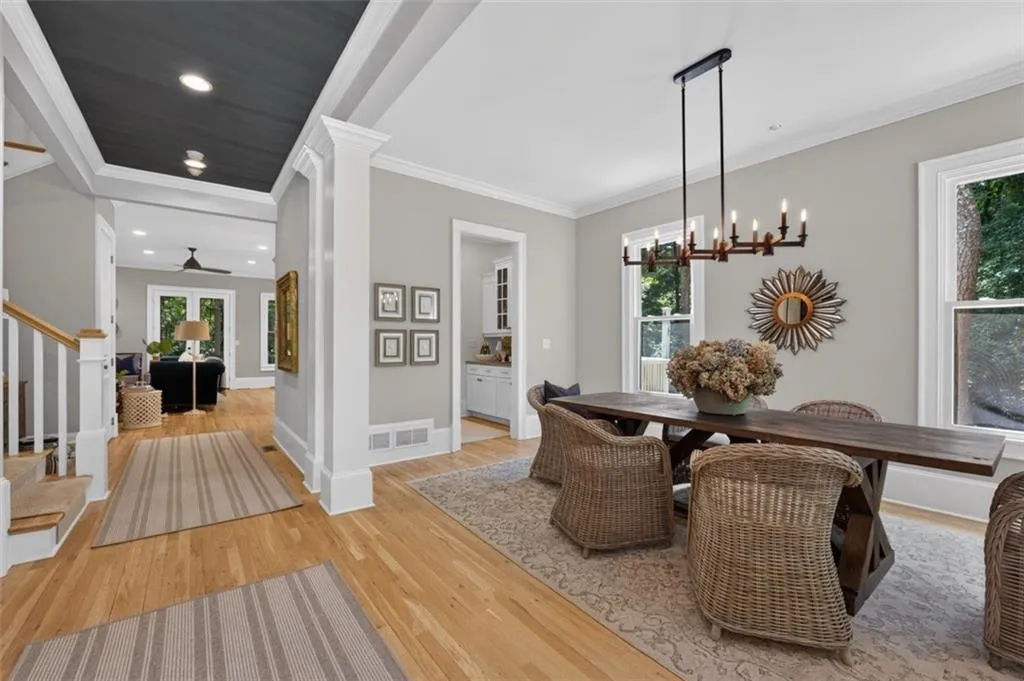 Dining area featuring a dark wood dining table, an extended linear chandelier, and light wood flooring