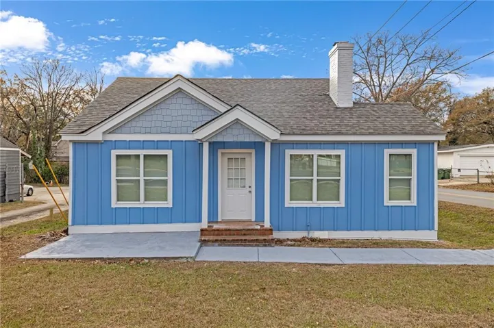 View of front facade featuring board and batten siding, roof with shingles, and a front yard