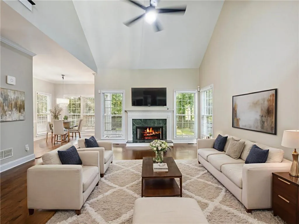 Living room with high vaulted ceiling, wood finished floors, a ceiling fan, healthy amount of natural light, and a fireplace