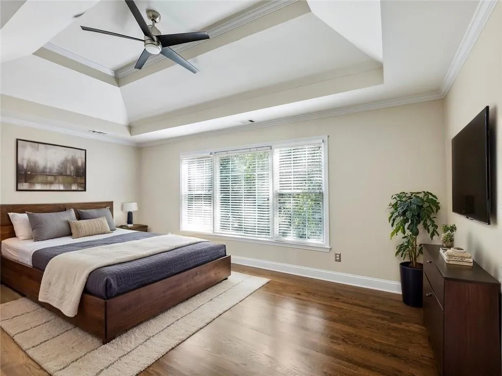Bedroom featuring a tray ceiling, dark wood finished floors, crown molding, and ceiling fan