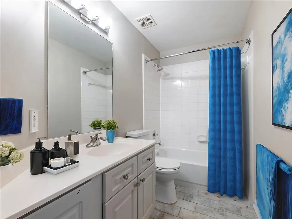 Bathroom with vanity, shower / bath combo, and marble look tile flooring