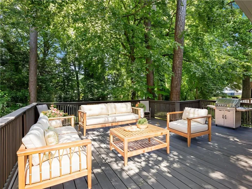 Wooden deck with outdoor lounge area, area for grilling, and view of scattered trees