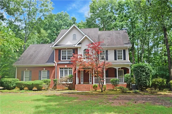 Brick and siding exterior featuring a covered front porch with white railings, a prominent gable, and dark shutters
