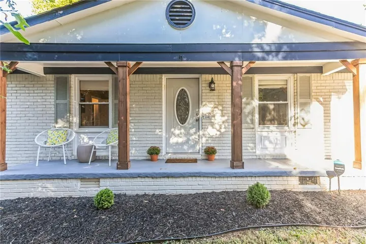 White brick exterior featuring a covered porch, wood posts, and a decorative oval glass entry door