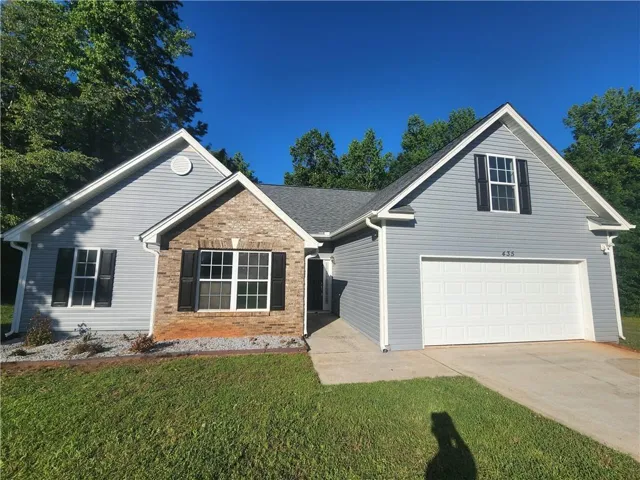 Light blue siding exterior with a partial brick facade, attached garage, and a concrete driveway
