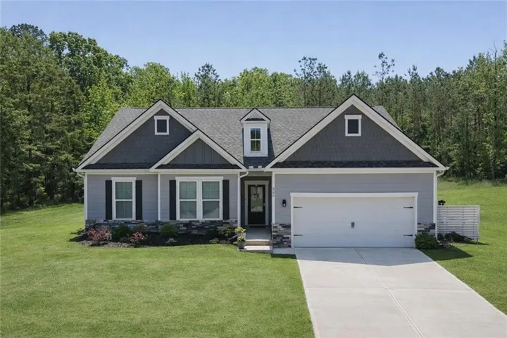 Contemporary residence featuring a two-car garage, light gray siding, dark gray shingle siding accents, stone veneer detailing, and a prominent front door