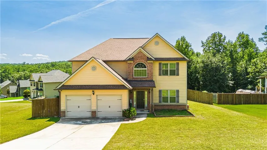 Two-story residence featuring a brick and siding exterior, an arched window, a two-car garage, and a concrete driveway
