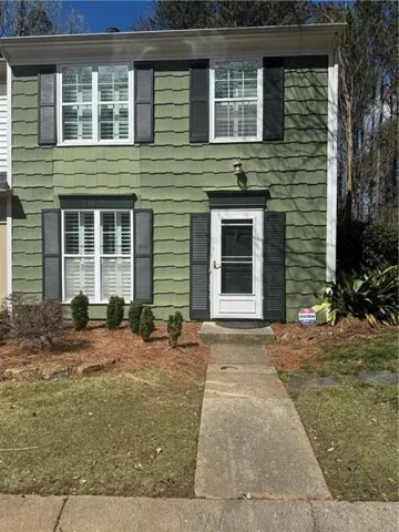 Two-story facade with green shingle-style siding and white trim accents