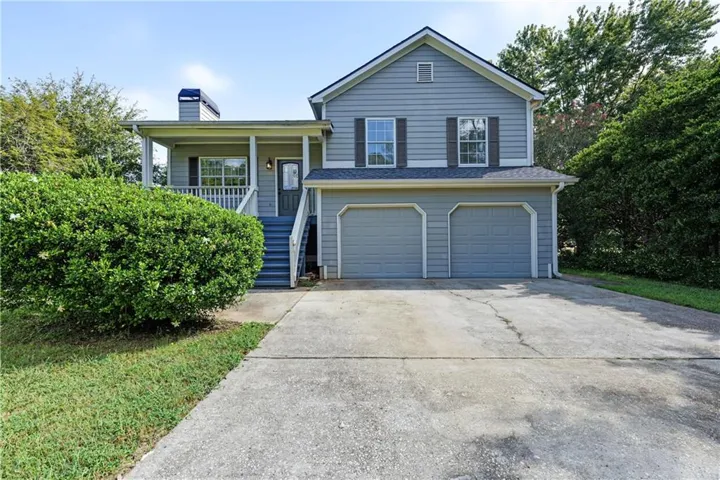 Two-story exterior with light blue siding, a covered front porch, a two-car garage, and a concrete driveway