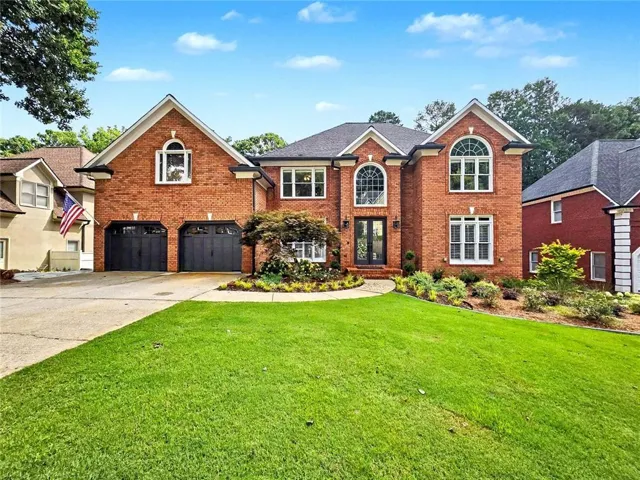 Traditional brick facade residence featuring a two-car garage with dark paneled doors
